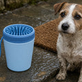 Blue silicone paw cleaner cup beside a wet terrier, included in the Muddy Walk Kit